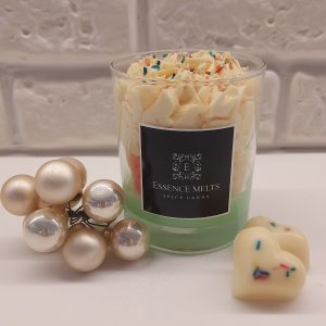 Spicy Candy candle in a glass jar with whipped cream-like topping, colorful sprinkles, and heart-shaped wax accents, displayed with pearl ornaments. Dessert candles