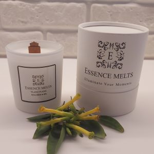 Ylang Ylang Spa Candle burning in a white glass container with a soft glowing flame. a exotic, floral scent. Spa Candles