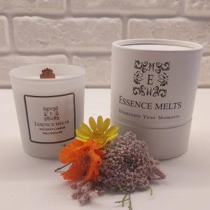 Patchouli Amber scented candle in white glass with cherry wood wick, placed on a stone surface. Spa Candles