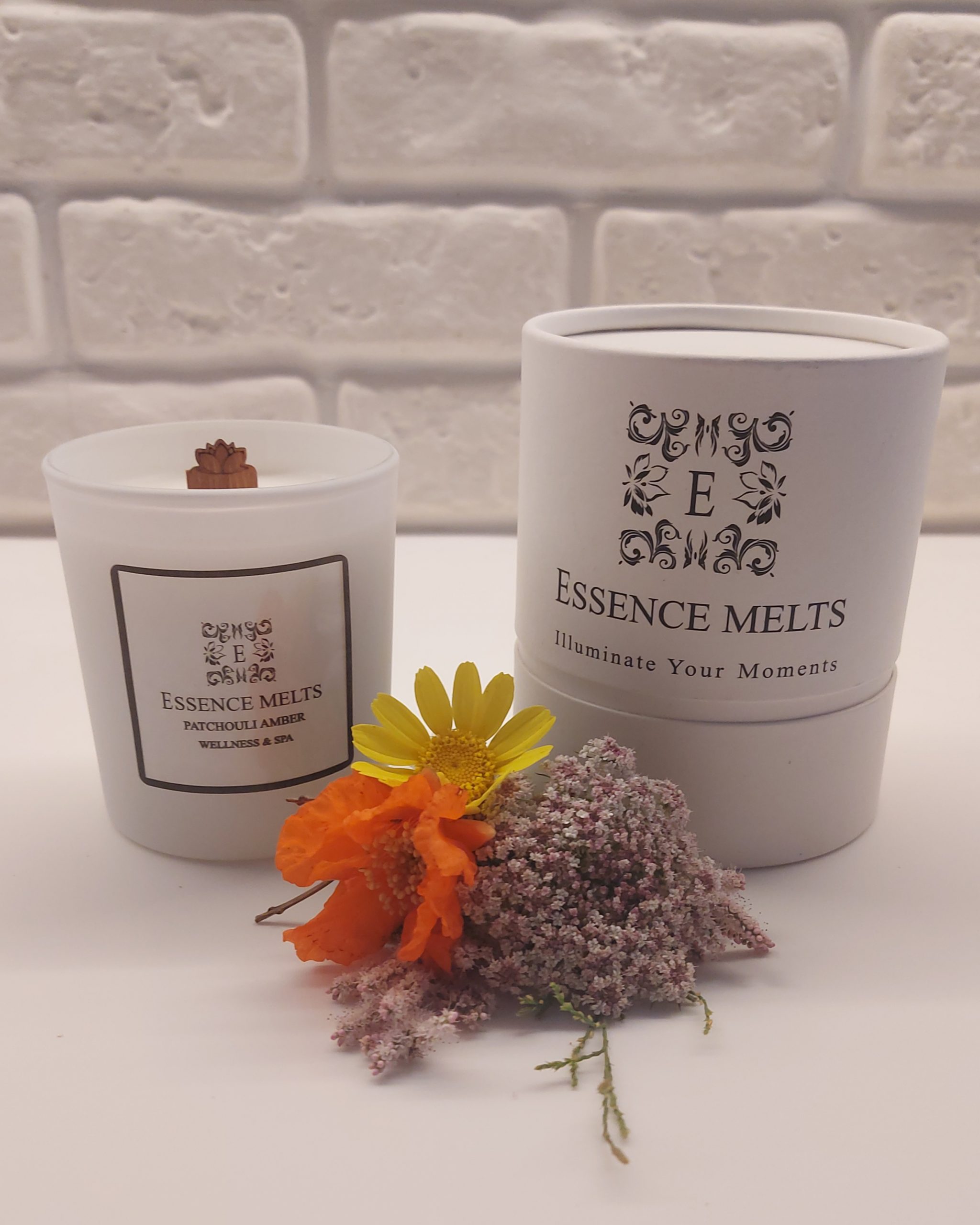 Patchouli Amber scented candle in white glass with cherry wood wick, placed on a stone surface. Spa Candles