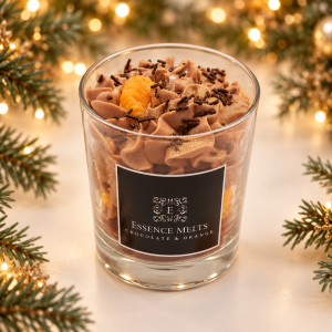 Orange Chocolate candle with brown whipped wax, chocolate-style sprinkles and an orange-shaped wax segment, against Christmas greenery and golden lights.