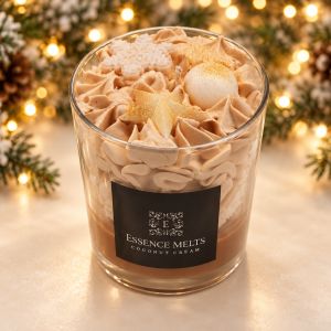 Coconut Cream scented candle with whipped wax, star and snowflake decorations, displayed against Christmas greenery and golden lights.