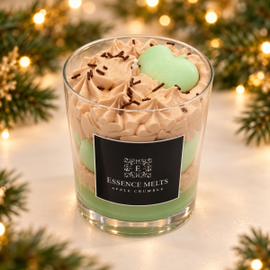 Apple Crumble candle with beige whipped wax and a green apple-shaped wax decoration, framed by Christmas greenery and golden lights.