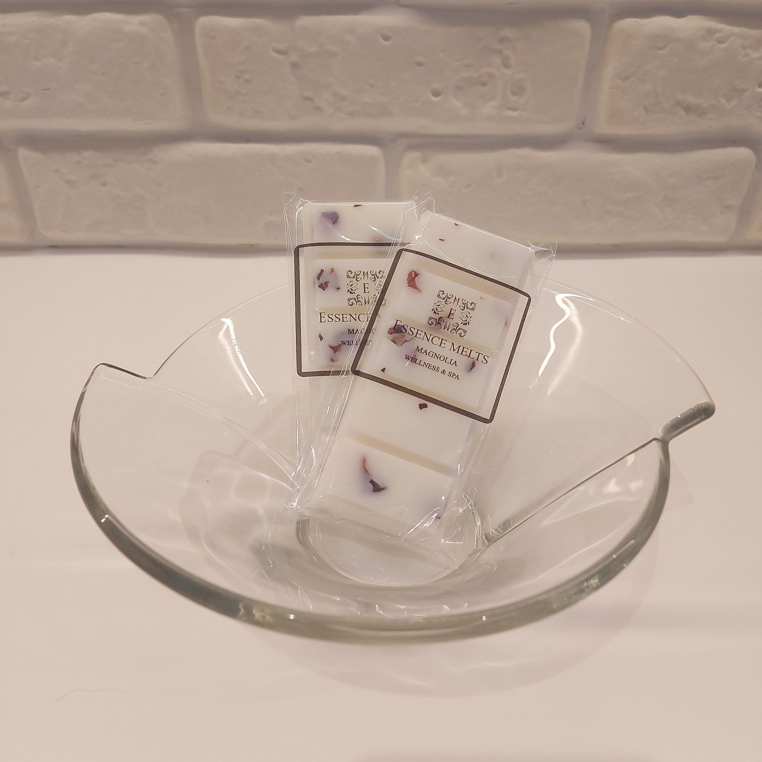 Magnolia-scented wax melt snap bar wrapped in a clear cellophane bag with the black Essence Melts logo.