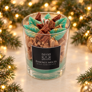 Mint Chocolate candle with green leaf-shaped and chocolate-bar-shaped wax decorations, framed by Christmas greenery and golden lights.