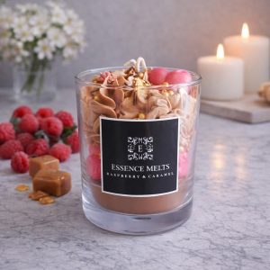 Raspberry Caramel candle in a glass jar with whipped caramel topping, chocolate sprinkles, and realistic raspberry wax accents, displayed with branded Essence Melts packaging. Dessert candles