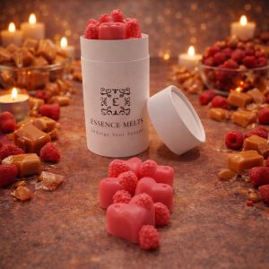 Raspberry Caramel scented wax melts in Essence Melts container styled with fresh raspberries, caramel cubes and warm candlelight background.
