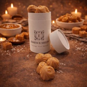 Salted Butter Caramel scented wax melts in Essence Melts container styled with caramel cubes, sea salt and cozy candlelight background.