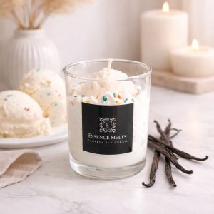 Vanilla Ice Cream scented candle by Essence Melts in clear glass jar with whipped wax topping, sprinkles, and vanilla pods on elegant marble background