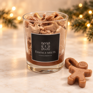 Essence Melts gingerbread scented candle in a glass jar with gingerbread-shaped wax decorations and warm Christmas lights behind.