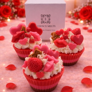 Three Valentine cupcake candles with heart, lips, chocolate and strawberry wax toppings, styled in a cozy romantic pink setting with rose petals and the Essence Melts gift box.