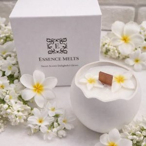 Monoi Egg 2 Candle in an elegant white cracked-egg-shaped vessel with floral wax accents and a cherry wood wick, placed beside a branded Essence Melts box.