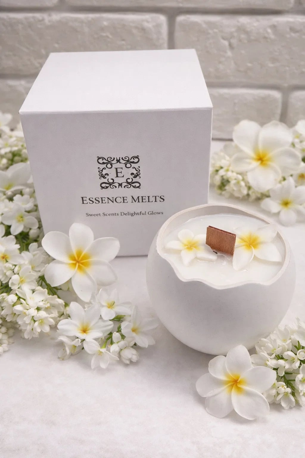 Monoi Egg 2 Candle in an elegant white cracked-egg-shaped vessel with floral wax accents and a cherry wood wick, placed beside a branded Essence Melts box.