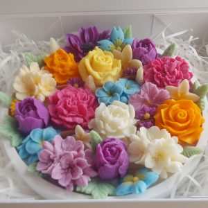 Handcrafted floral candle with colorful wax flowers in a white ribbed heat resistant bowl