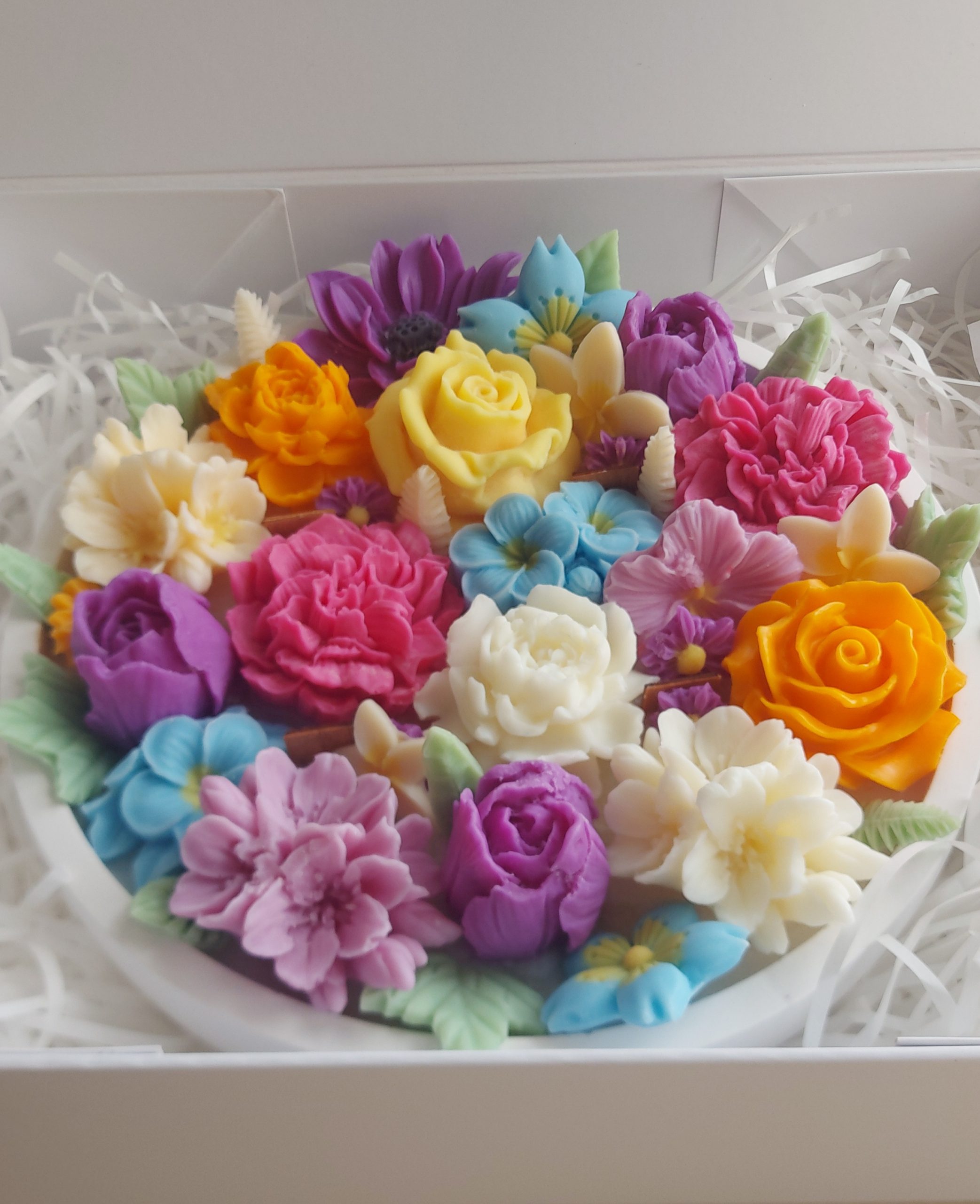 Handcrafted floral candle with colorful wax flowers in a white ribbed heat resistant bowl