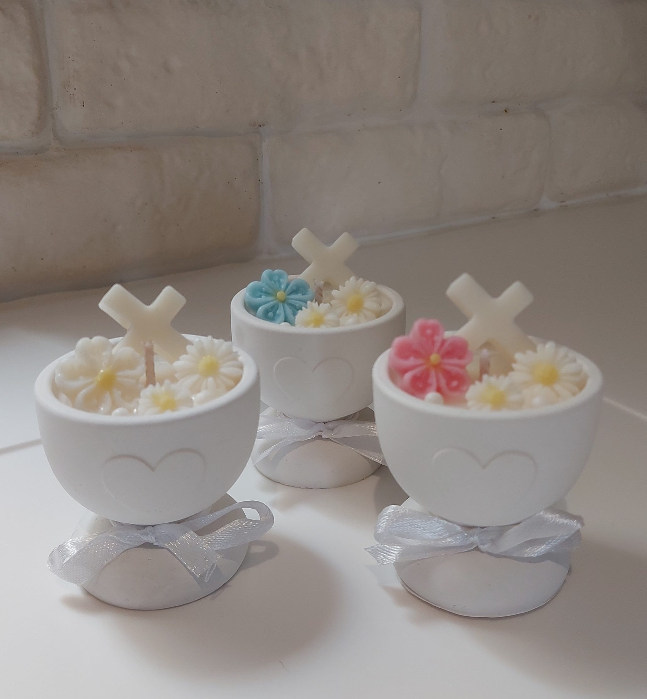 Three small chalice cross religious candles with a small cross and flowers