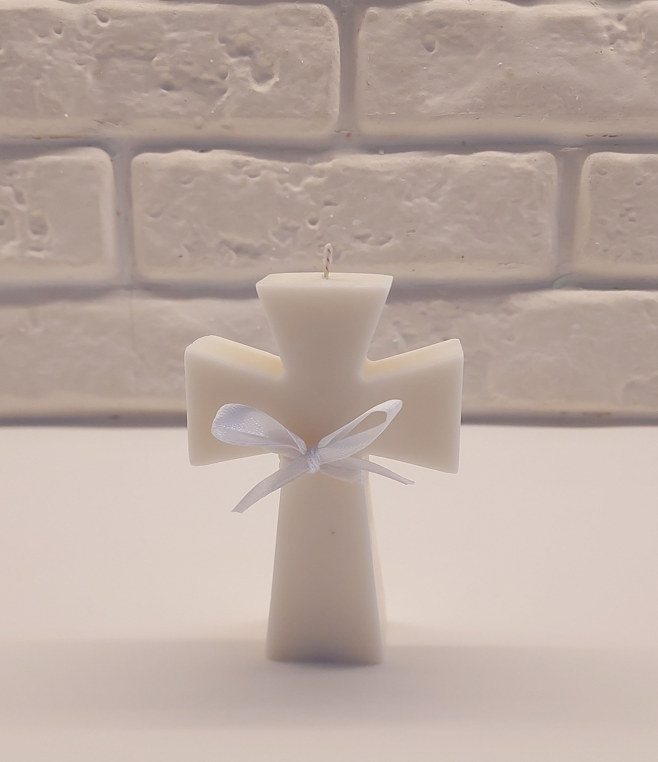 A white cross holy communion candle elegantly tied with a white ribbon, symbolizing purity and remembrance.