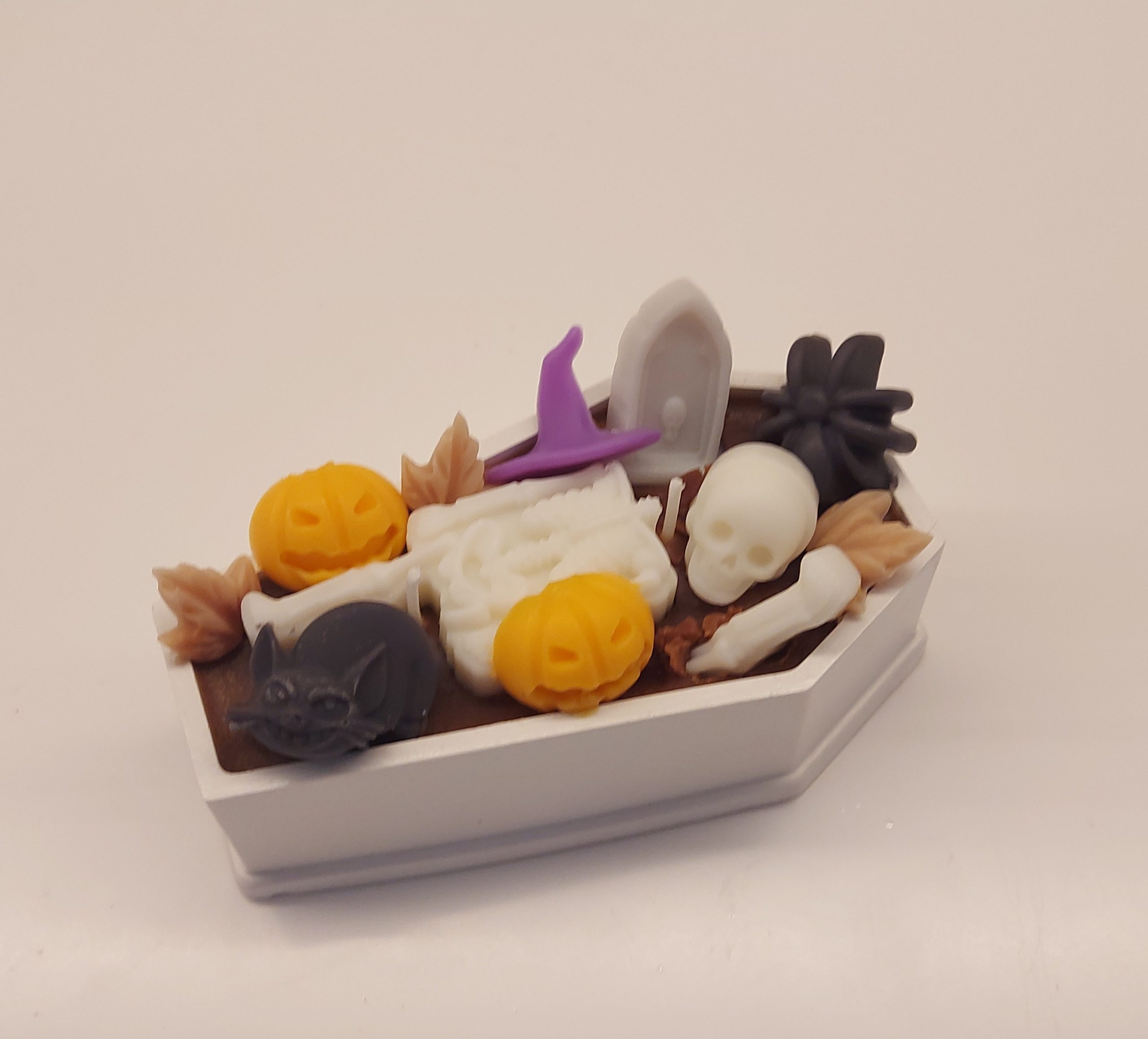 Halloween coffin candle with brown coconut/soy wax, decorated with skeleton, tombstone, black spiders, and orange pumpkins. Spicy vanilla, almond, coconut, and musky fragrance.