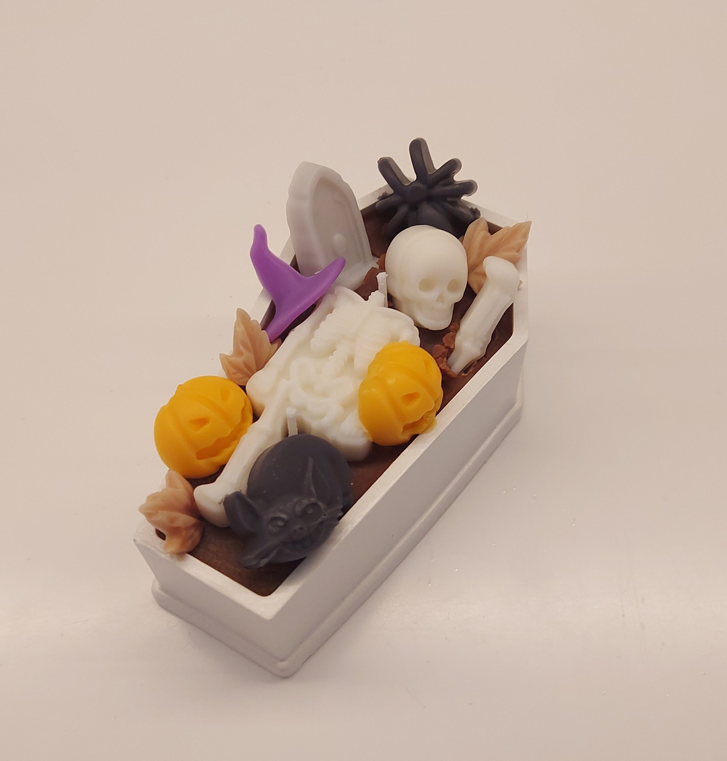 Halloween coffin candle with brown coconut/soy wax, decorated with skeleton, tombstone, black spiders, and orange pumpkins. Spicy vanilla, almond, coconut, and musky fragrance.