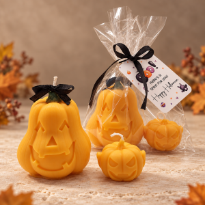 Orange Halloween Pumpkin Duo candles in two sizes, displayed beside a cellophane-wrapped set with a black ribbon and Halloween tag.